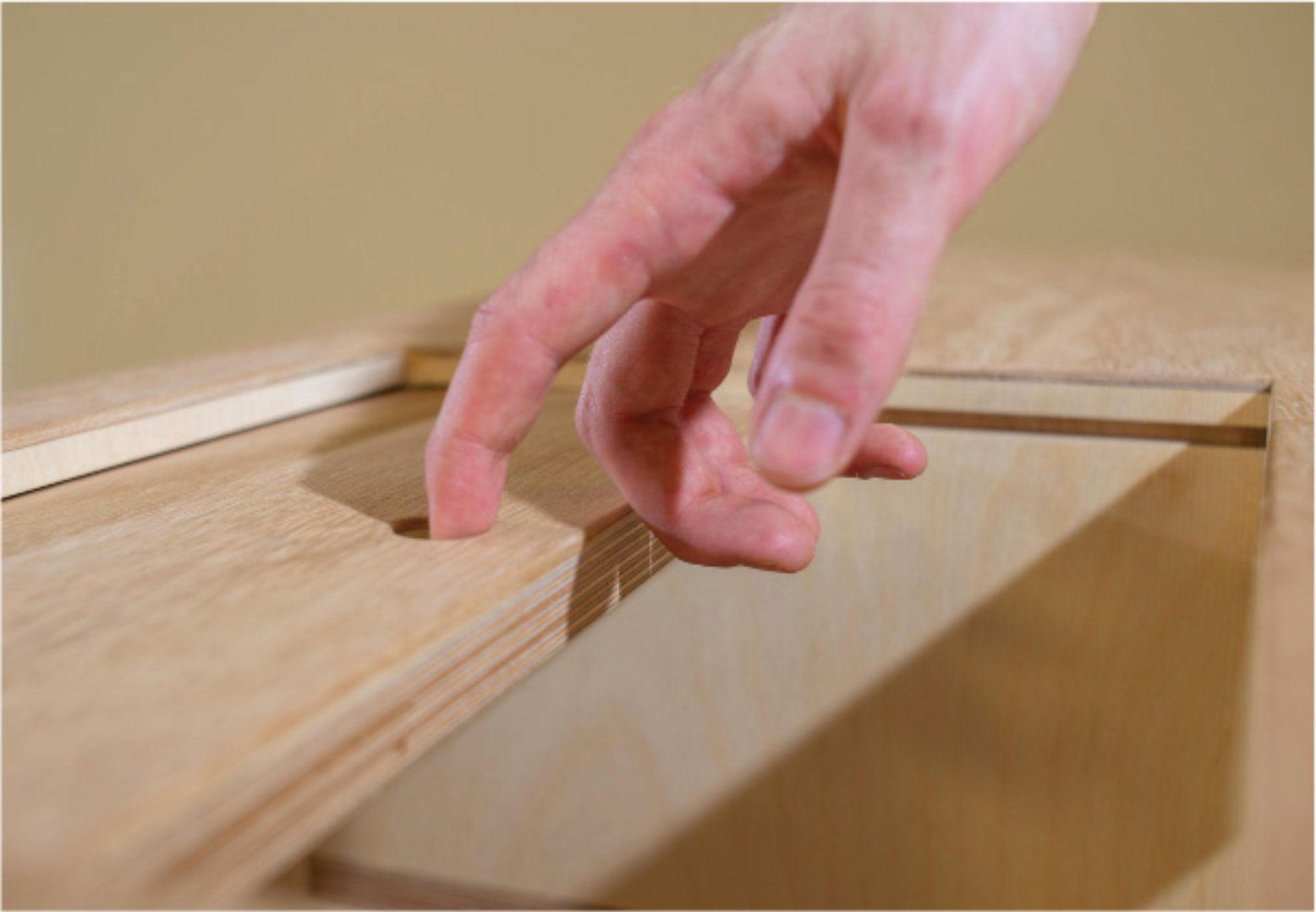 A hand sliding the plywood top panel open